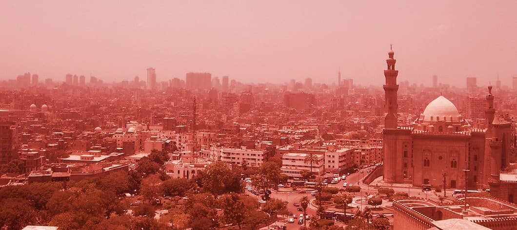 Cairo's skyline, with the minaret and dome of a historic mosque in the foreground.